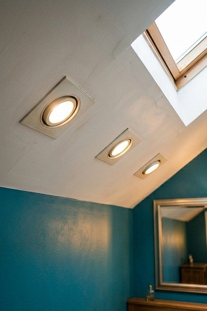 Angled recessed lighting fixtures installed in a sloped attic bathroom ceiling