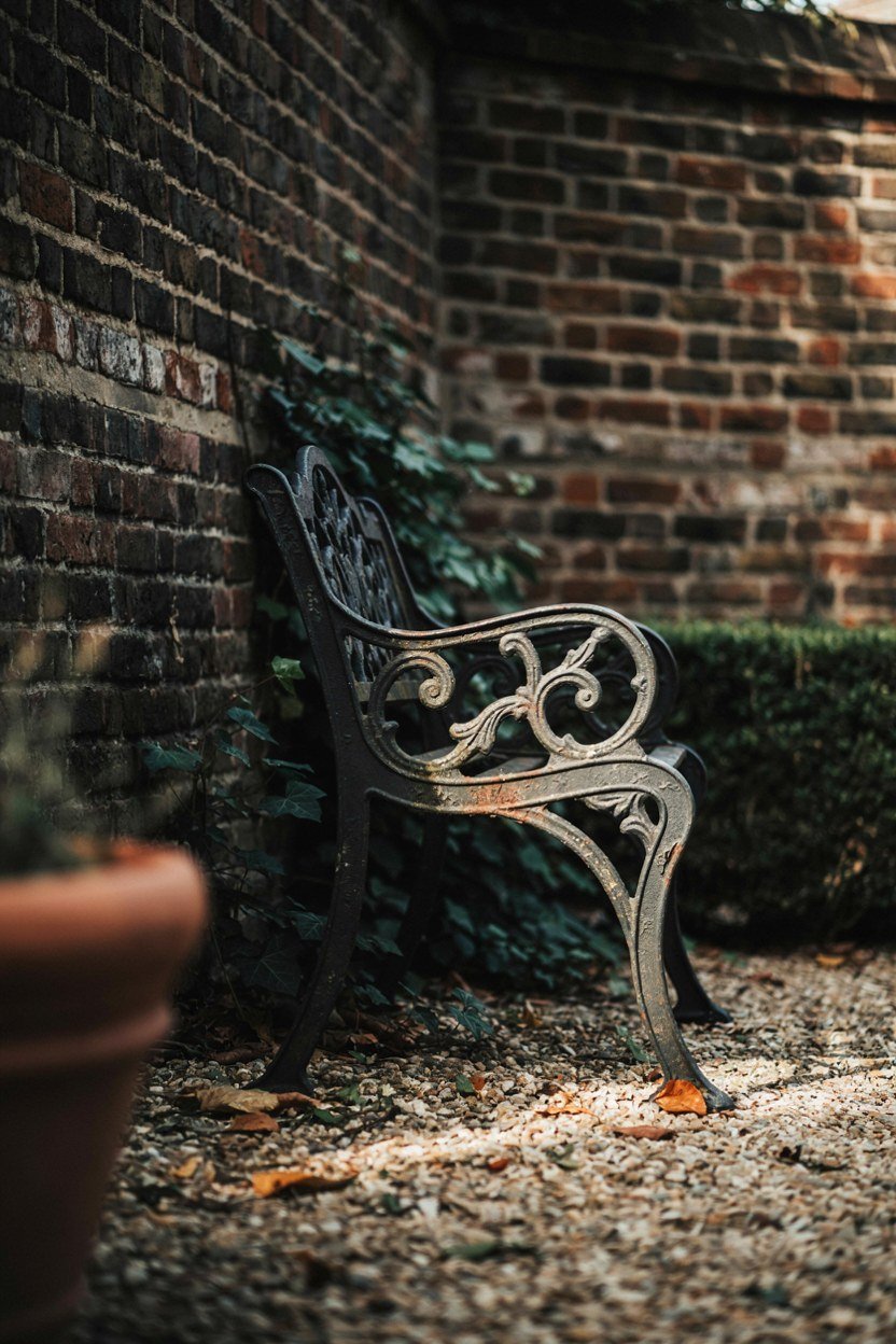 Reclaimed cast iron bench standing against a dark garden wall
