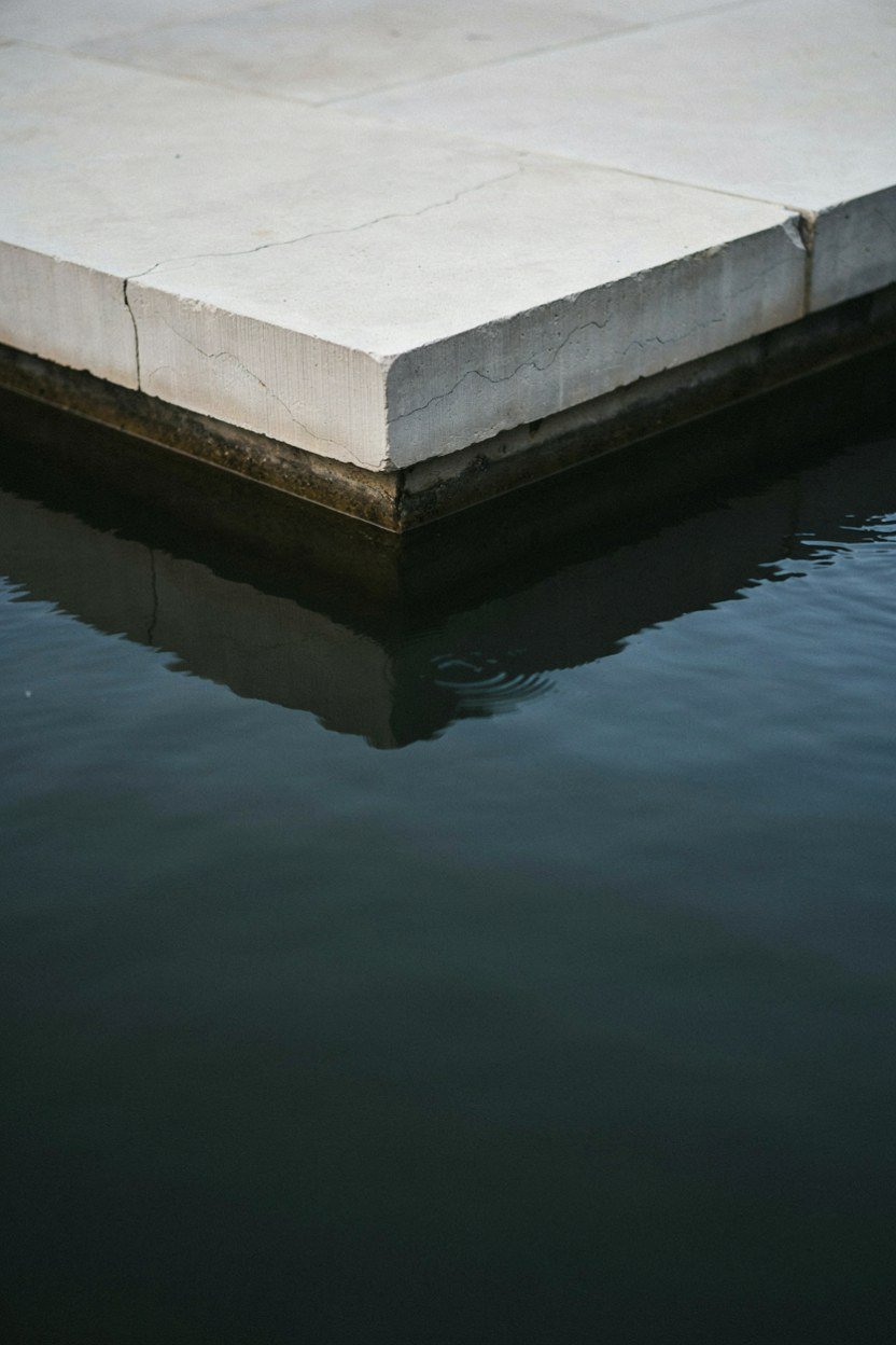 Sawn stone coping forming a crisp overhanging edge on a pond