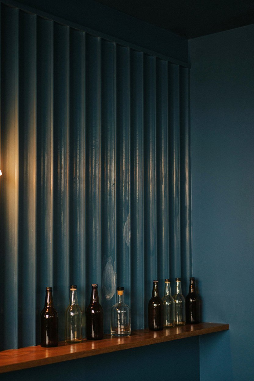 Fluted glass back panel behind a row of bottles in a blue bar alcove