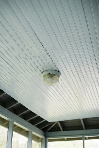 A pale blue white beadboard ceiling on a screened porch