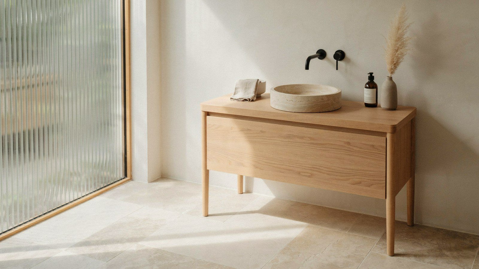 Japandi bathroom with a pale oak vanity on a honed stone floor
