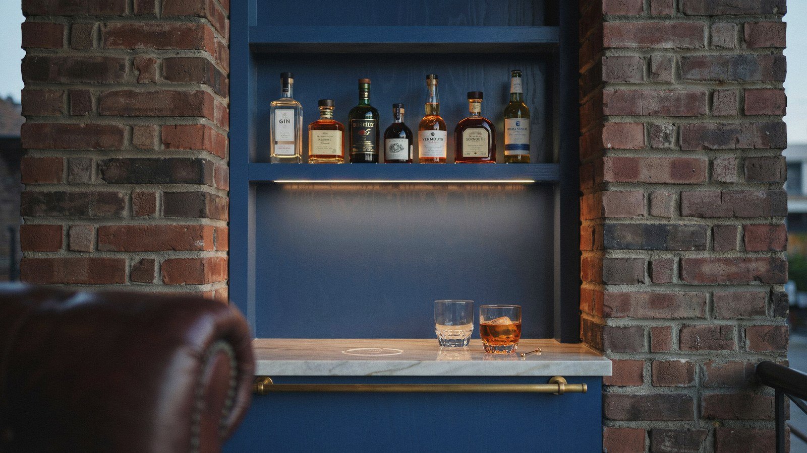 Midnight blue home bar built into a chimney alcove with a pale stone counter