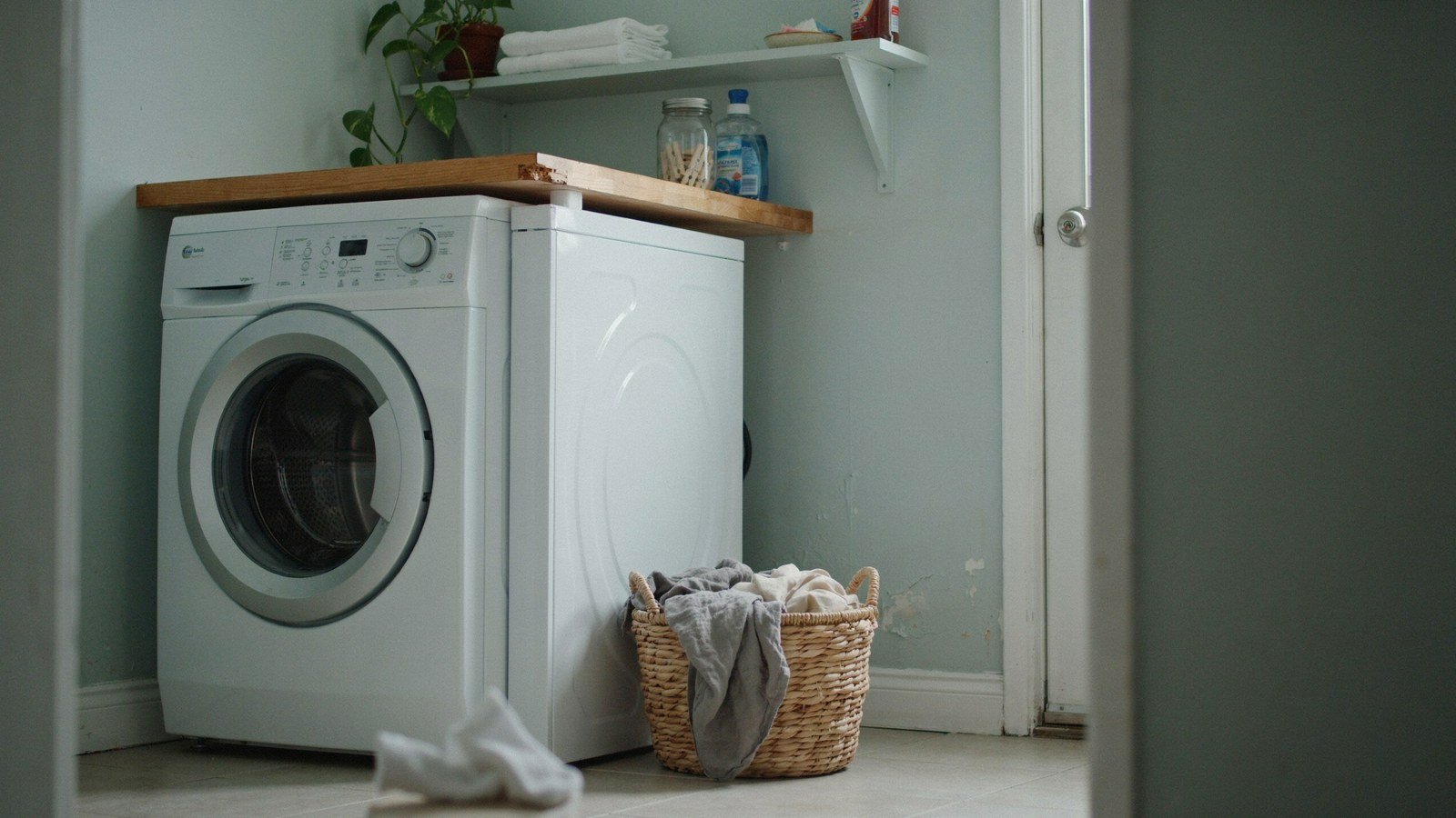 Compact laundry nook with stacked washer and dryer under a wooden folding counter