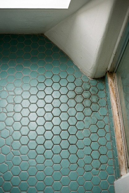 Small teal hexagon tile flooring in an attic bathroom with angled walls