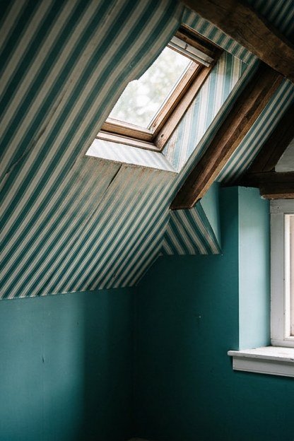 Teal and white striped wallpaper applied to a sloped attic bathroom ceiling