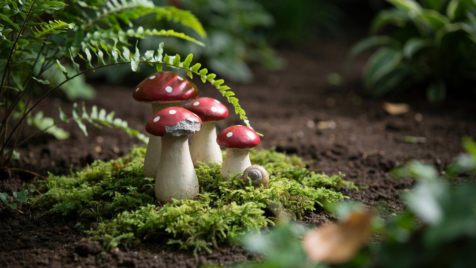 Cluster of painted toadstool sculptures tucked under ferns in a shady garden bed