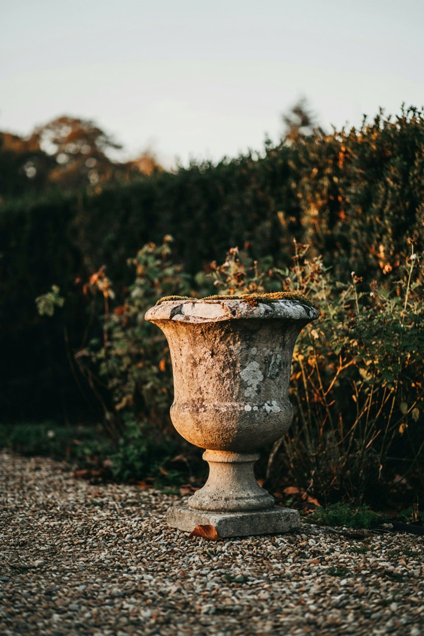 Weathered stone urn placed at the end of a garden sightline